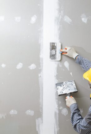 interior decoration construction furniture builtin.Plasterer in working uniform plastering the wall indoors.
